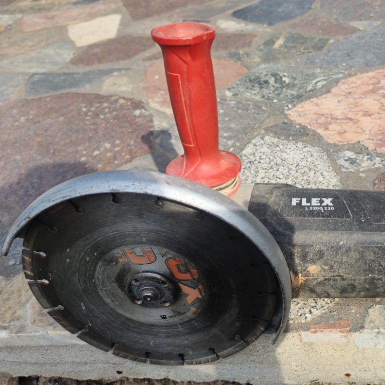 Schneidemaschine mit rotem Griff und schwarzem Gehäuse auf einem Bodenbelag.